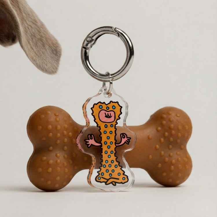 Fur Sie Zen Master charm in front of a brown rubber bone toy. The acrylic charm mimics the toy's bumpy surface and bone shape for a meditative dog persona