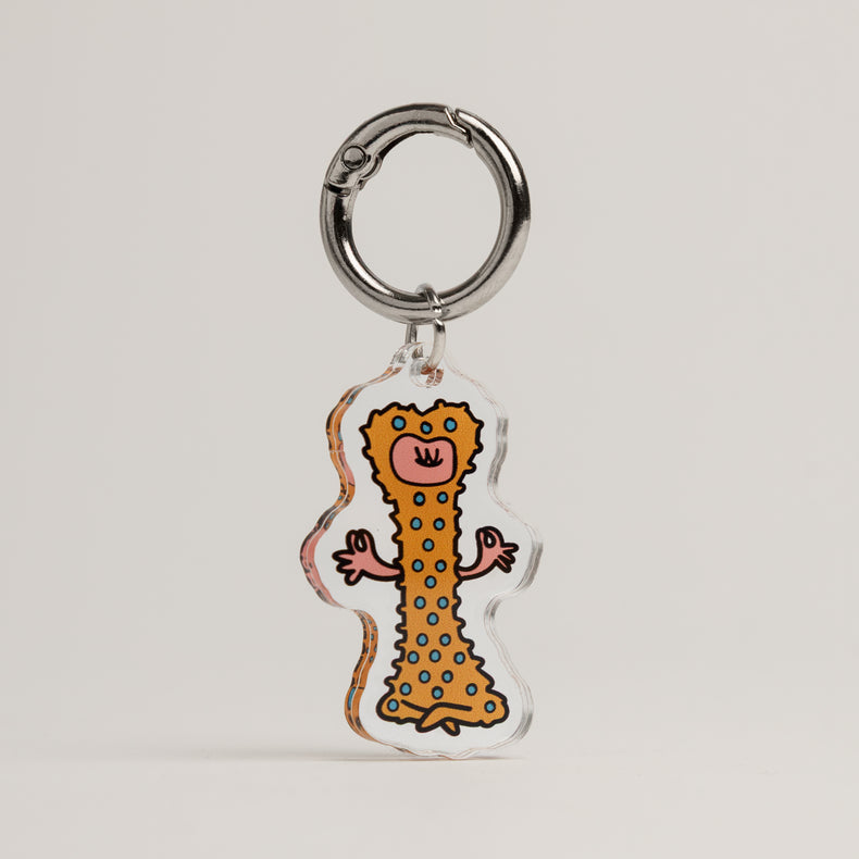 Fur Sie Zen Master dog charm: A brown acrylic accessory with blue polka dots, shaped like a textured rubber bone. Features a character in a meditative yoga pose
