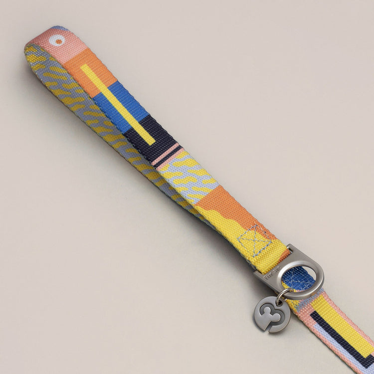 Una leash handle with D-ring and Fur Sie charm on a gray background