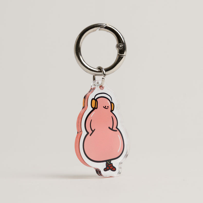 A pink acrylic FurSie charm in the shape of a classic Kong chew toy, featuring a cartoon character wearing orange headphones and red sneakers. Shown clipped to a silver metal keyring against a neutral background